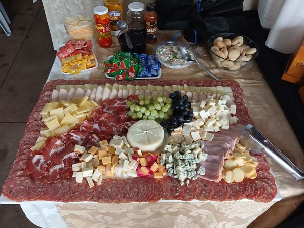 Mesa de frios com salame, presunto, queijos e uvas